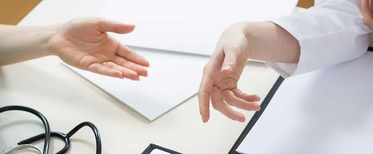la mano di un dottore sta per prendere quella di un paziente, a dimostrazione del suo supporto 