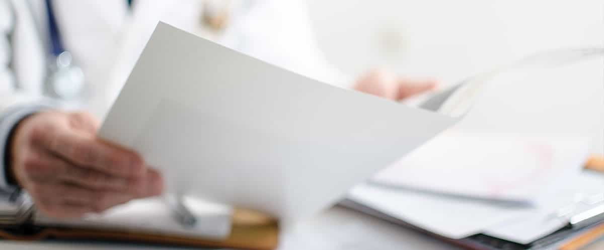Mano di un un medico che analizza un referto posto in primo piano