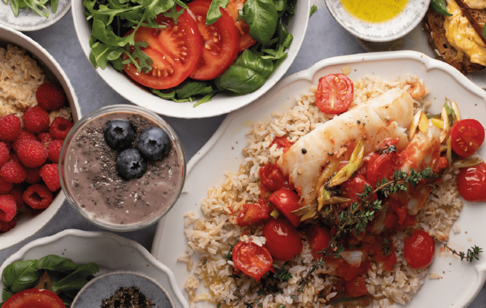 Foto di un tavolo imbandito con cibo sano: pesce, riso, insalata, smoothie e avena.