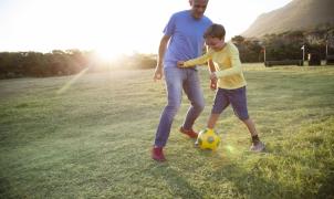 Papà e figlio giocano a calcio insieme. 