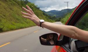 Un braccio che sporge dal finestrino di un'auto in movimento su una strada di campagna.   